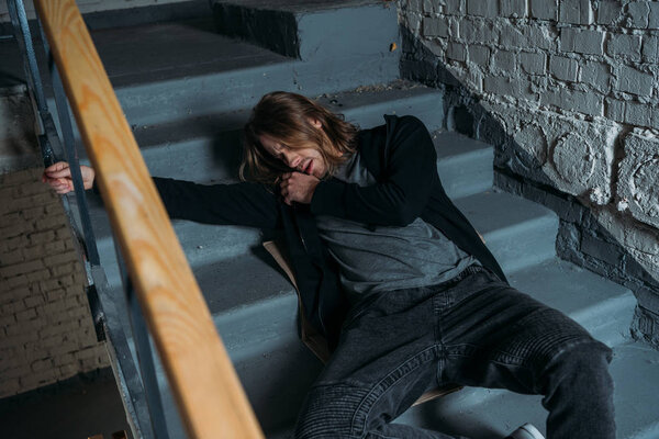 addicted junkie lying on stairs after taking dose