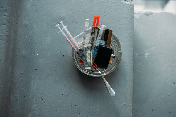 top view of can with heroin syringes and various objects