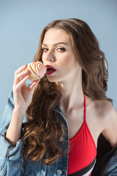 Verleidelijke Vrouw Rode Zwembroek Cupcake Eten Kijken Naar Camera Geïsoleerd — Gratis stockfoto