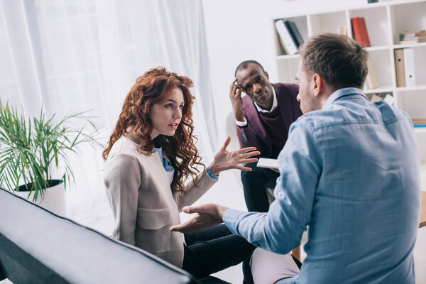 Arguing couple on sofa and african american counselor in office