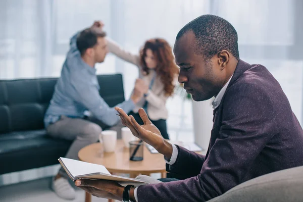 Boos Afrikaanse Amerikaanse Counselor Zoek Leerboek Terwijl Scheidend Paar Gevechten — Stockfoto