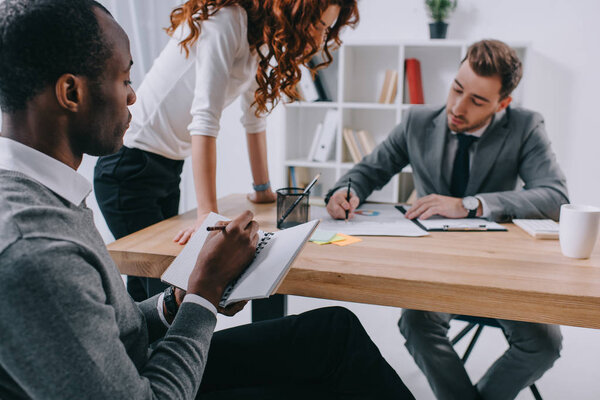 Multicultural business colleagues working at table in office