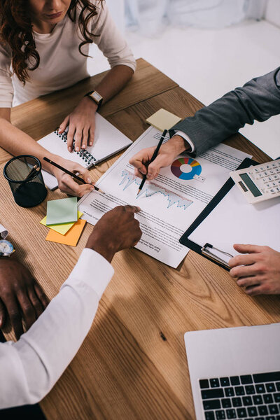 Команда деловых партнеров занимается бумажной работой, сидя за столом
 