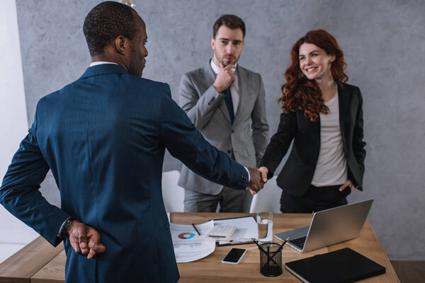 Businessman with fingers crossed shaking hand to partner 