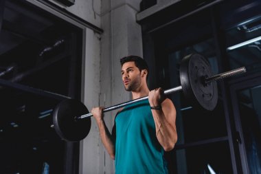 sportsman lifting barbell during cross training in gym clipart
