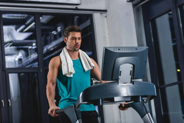 tired sportsman with towel exercising on treadmill in sports center