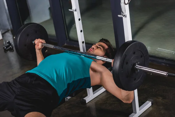 strong sportsman training with barbell in sports hall