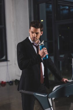 manager in suit training on treadmill with sport bottle in gym clipart