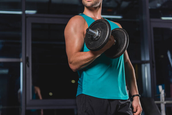 cropped view of muscular sportsman training with dumbbell 