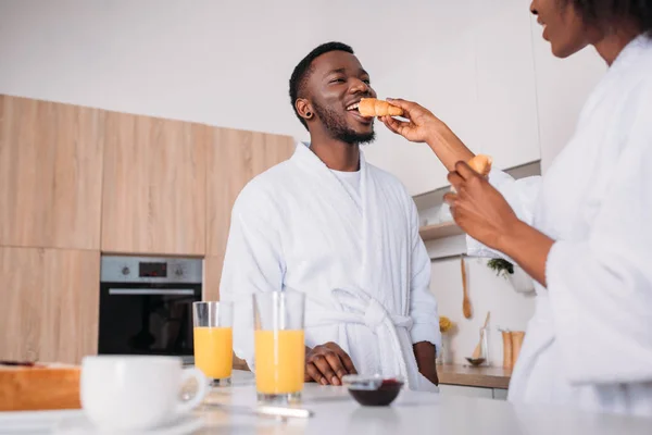 非洲裔美国妇女在厨房里用牛角面包喂养男友的低角度视角 — 图库照片