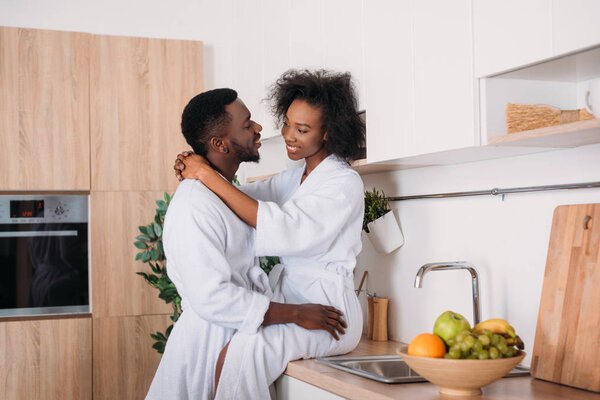 Smiling african american couple hugging in kitchen