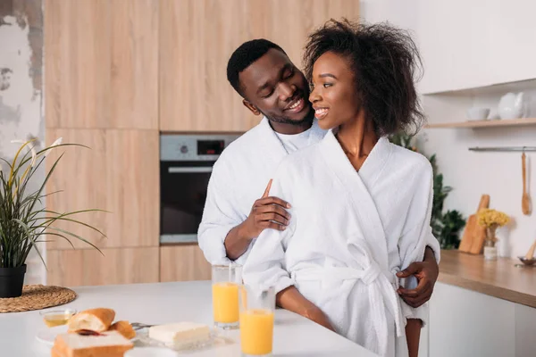 微笑的非洲裔美国人夫妇站在餐桌上 早餐在厨房 — 图库照片