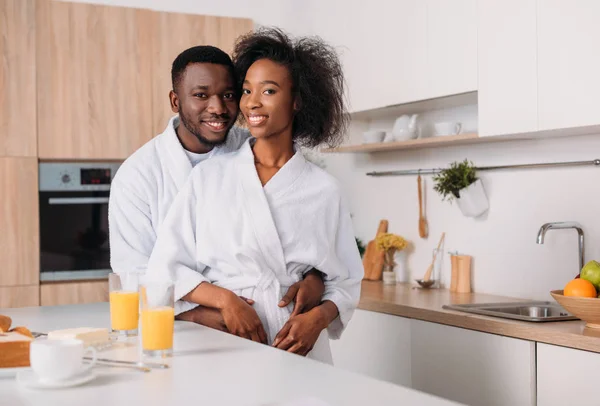年轻的微笑非洲裔美国人夫妇拥抱在厨房里 — 图库照片