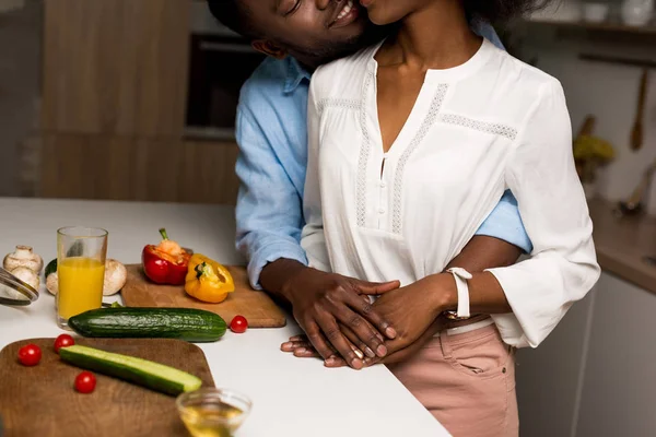 在餐桌旁抱着蔬菜的年轻非洲裔美国夫妇的裁剪图像 — 图库照片