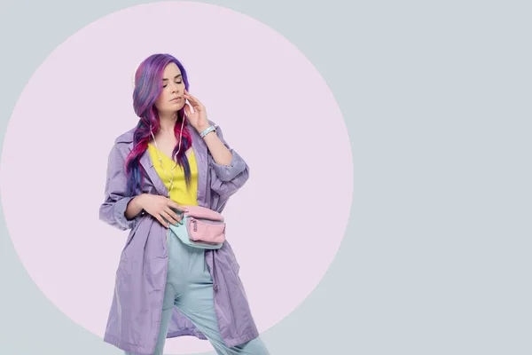 Красива Молода Жінка Фіолетовому Траншеї Слухає Музику Навушниками Творчому Фоні — стокове фото