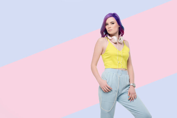 молодая женщина с наушниками висит на шее на творческом фоне
