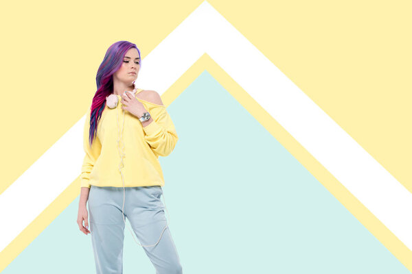 стильная молодая женщина с наушниками висит на шее на творческом фоне
