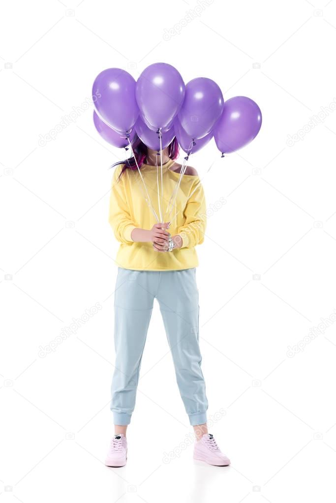 stylish young woman covering face with bunch of helium balloons isolated on white