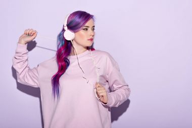 dancing young woman in pink clothes listening music with headphones clipart
