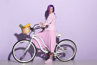 pembe giyim ananas ile bisiklet üzerinde genç kadın ve muz sepet içinde yan görünüm
