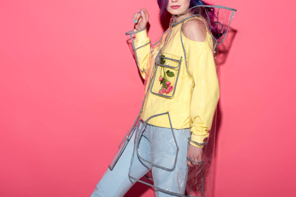 обрезанный снимок модной молодой женщины в прозрачном плаще на красном
