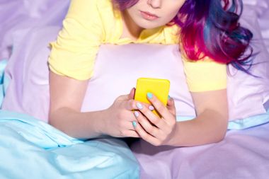 genç kadın yatakta smartphone kullanarak atış kırpılmış