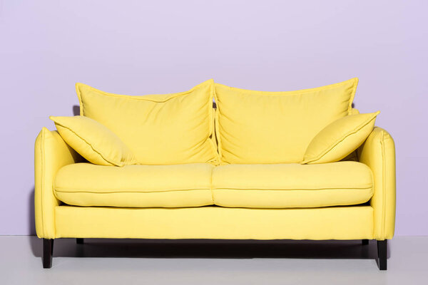удобный желтый диван перед розовой стеной

