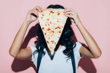 parça pizza üzerinde pembe bir arka plan ile yüz kapsayan kadının gizlenmiş görünümü
