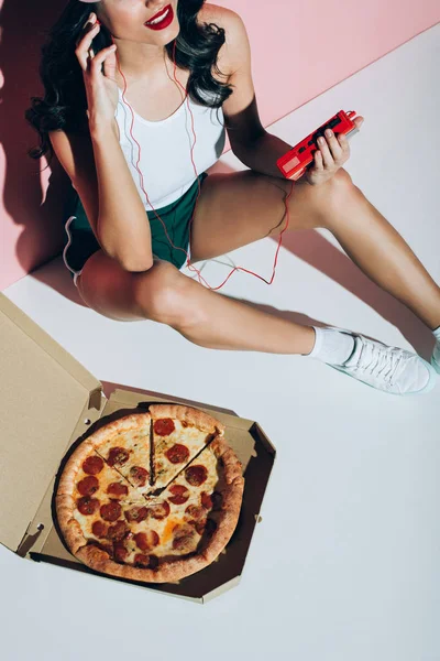 ピンクの背景にピザとレトロな音楽プレーヤーと配信ボックスの笑顔の女性のクロップ撮影 — ストック写真
