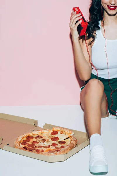 ピンクの背景にピザとレトロな音楽プレーヤーと配信ボックスの笑顔の女性のクロップ撮影 — ストック写真