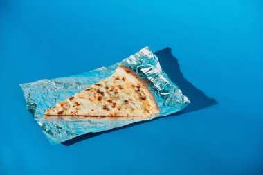 parça peynir İtalyan pizza görünümü üzerinde mavi arka plan folyoyu kadar kapatın