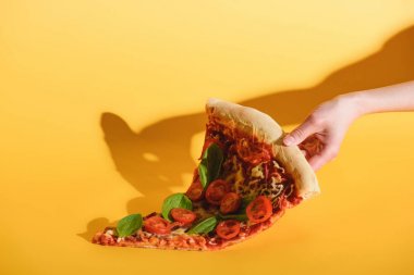 parça pizza domates ile sarı zemin üzerine elinde tutan kadın kısmi görünümünü