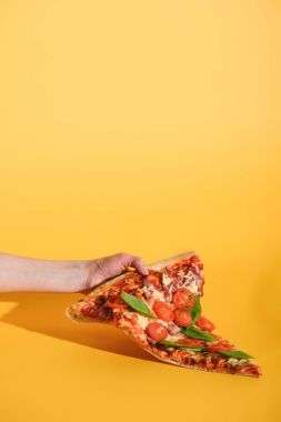 parça pizza domates ile sarı zemin üzerine elinde tutan kadın kısmi görünümünü
