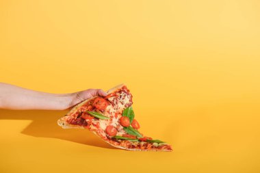 parça pizza domates ile sarı zemin üzerine elinde tutan kadın kısmi görünümünü