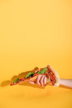 parça pizza Sarı zemin üzerine elinde tutan kadın kısmi görünümünü