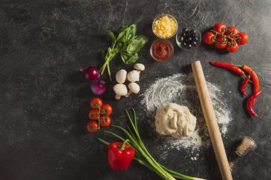 oklava, çiğ hamur ve taze malzemelerle pizza karanlık yüzeyi düz lay