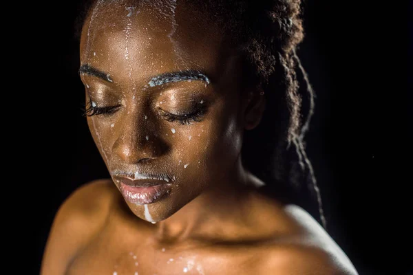 美丽的感官年轻的非洲裔美国妇女与溢出的牛奶在脸上孤立的黑色 — 免费的图库照片