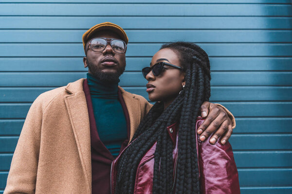stylish african american couple in fashionable clothes posing together outside