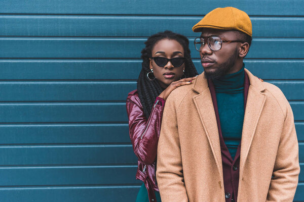 beautiful stylish young african american couple in jacket and overcoat posing together outside 