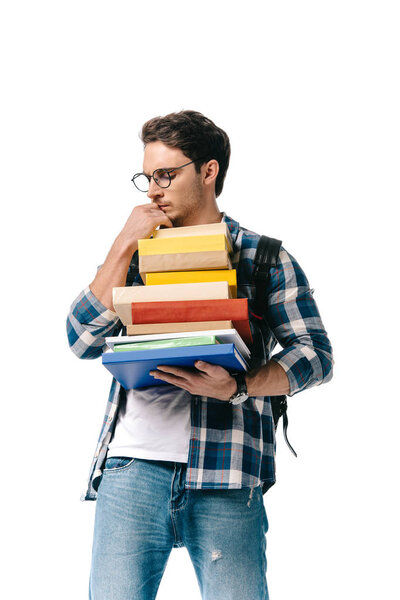 pensive handsome student holding stack of books isolated on white