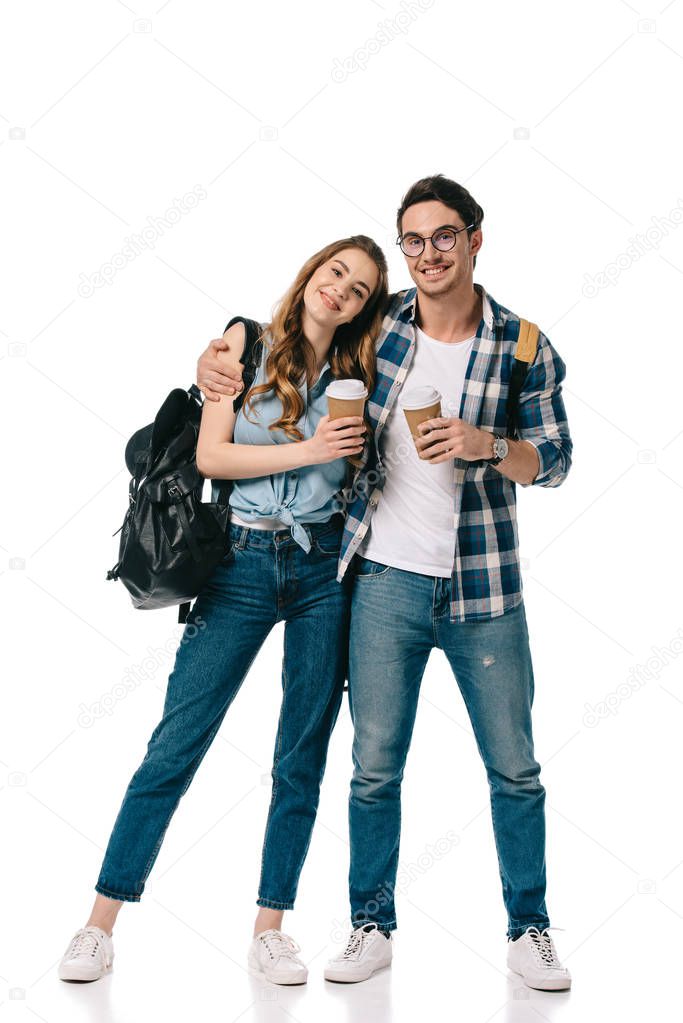 young students hugging and holding disposable coffee cups isolated on white