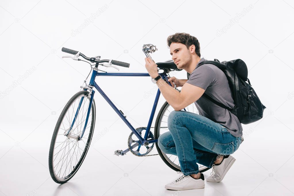 handsome student repairing bicycle on white