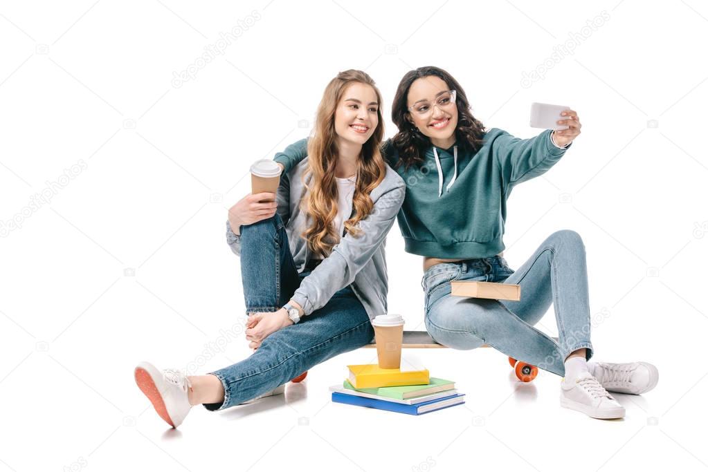 smiling multicultural students taking selfie with smartphone isolated on white