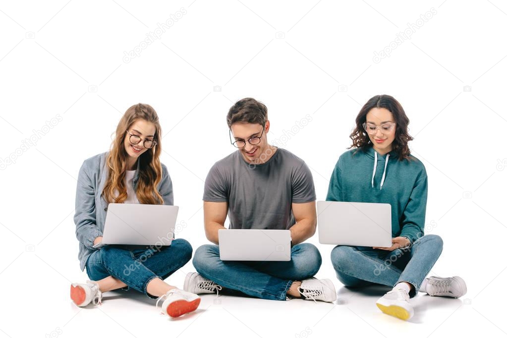 happy multicultural students using laptops on white