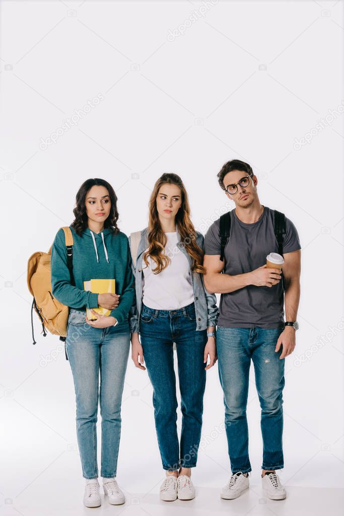 confused multicultural students looking away on white