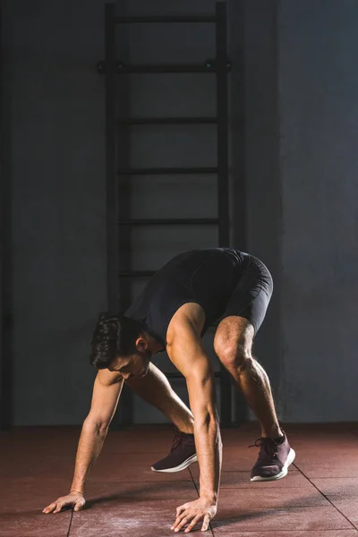 Young sportsman preparing to do push ups in sports hall