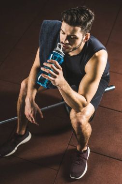 Sporcu içme suyu şişesi ve halter salonunda oturup yüksek açılı görünüş