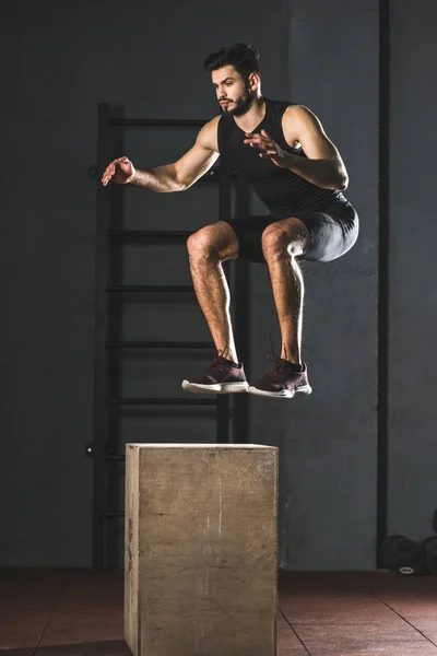 若いスポーツマン ジムで木製のブロックにジャンプ — ストック写真