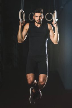 Sporcu spor merkezi jimnastik halkaları üzerinde egzersiz yaparak önden görünümü