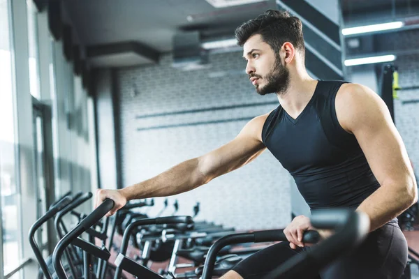 Vista Lateral Del Joven Deportista Haciendo Ejercicio Bicicleta Estática Centro — Foto de Stock